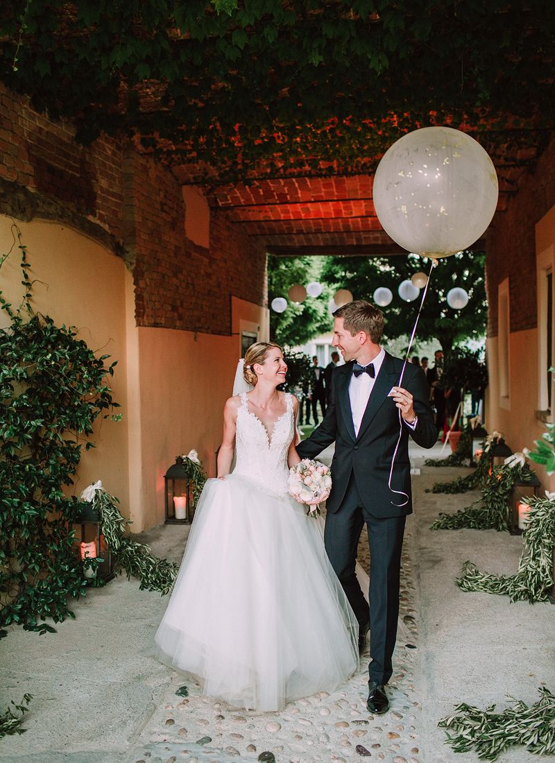 bride and groom getting walking through stone arch at la villa hotel mombaruzzo