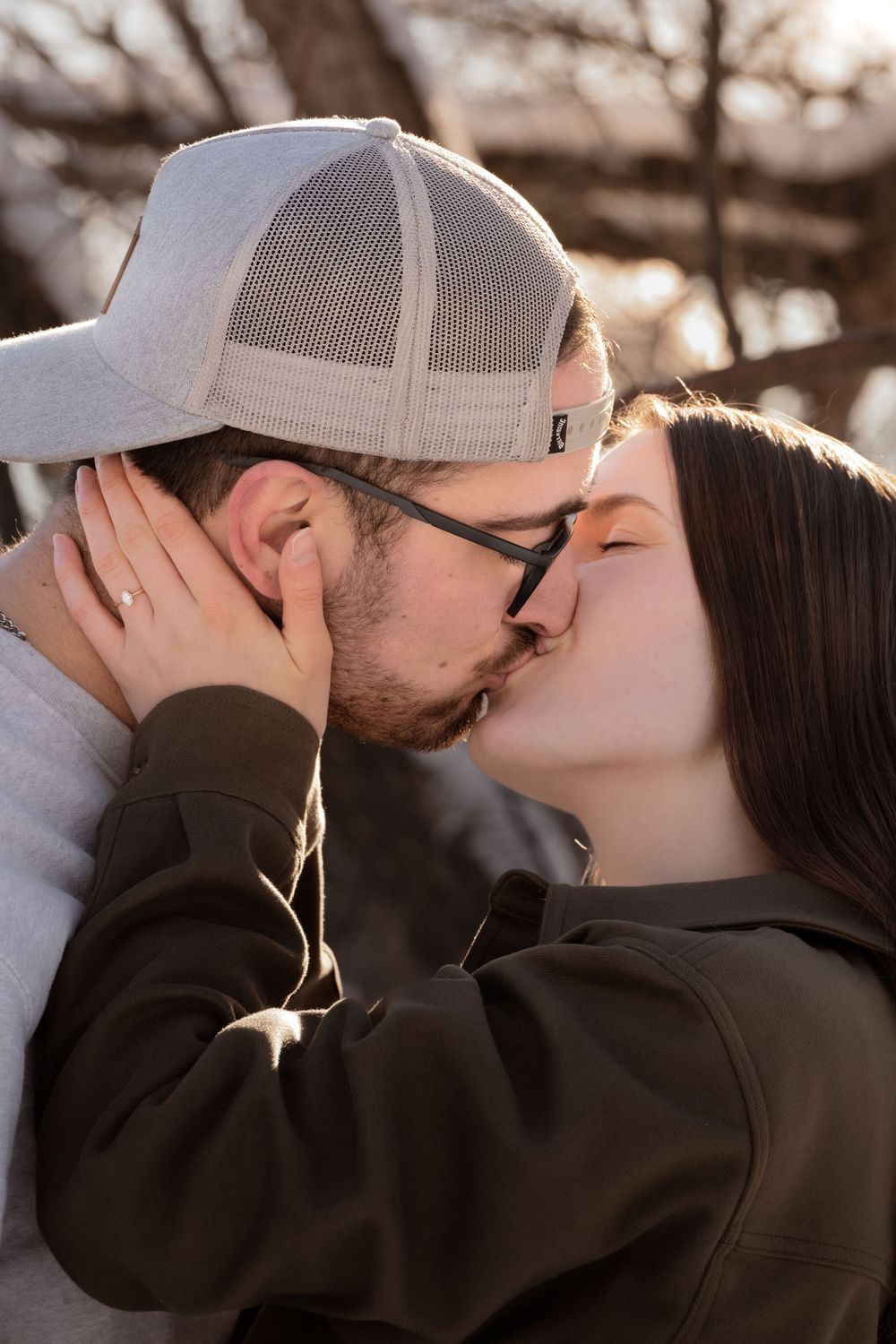 A romantic couple sharing multiple tender kisses while wearing casual winter attire outdoors.