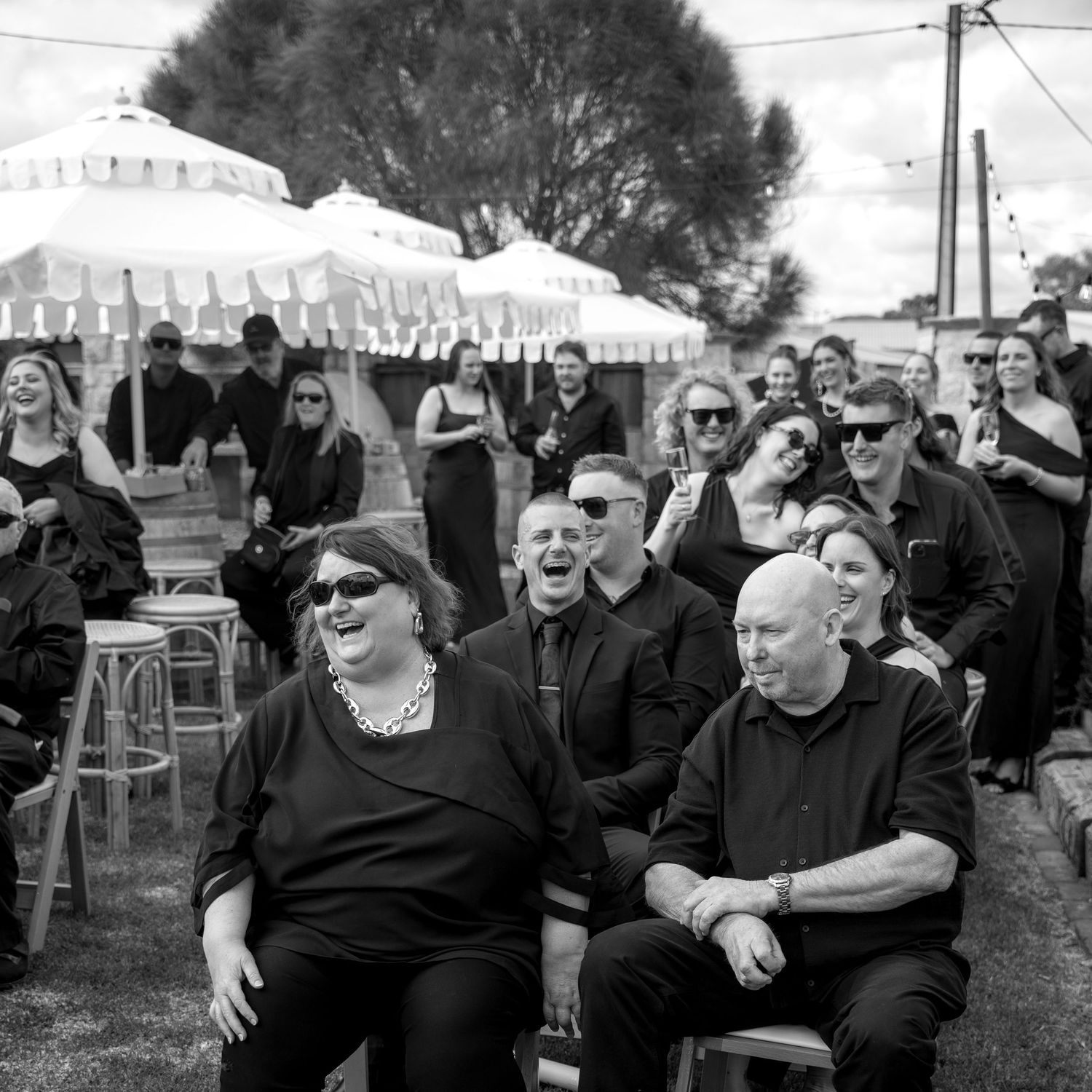 A black and white panoramic photograph showing people laughing and enjoying themselves at an outdoor event.