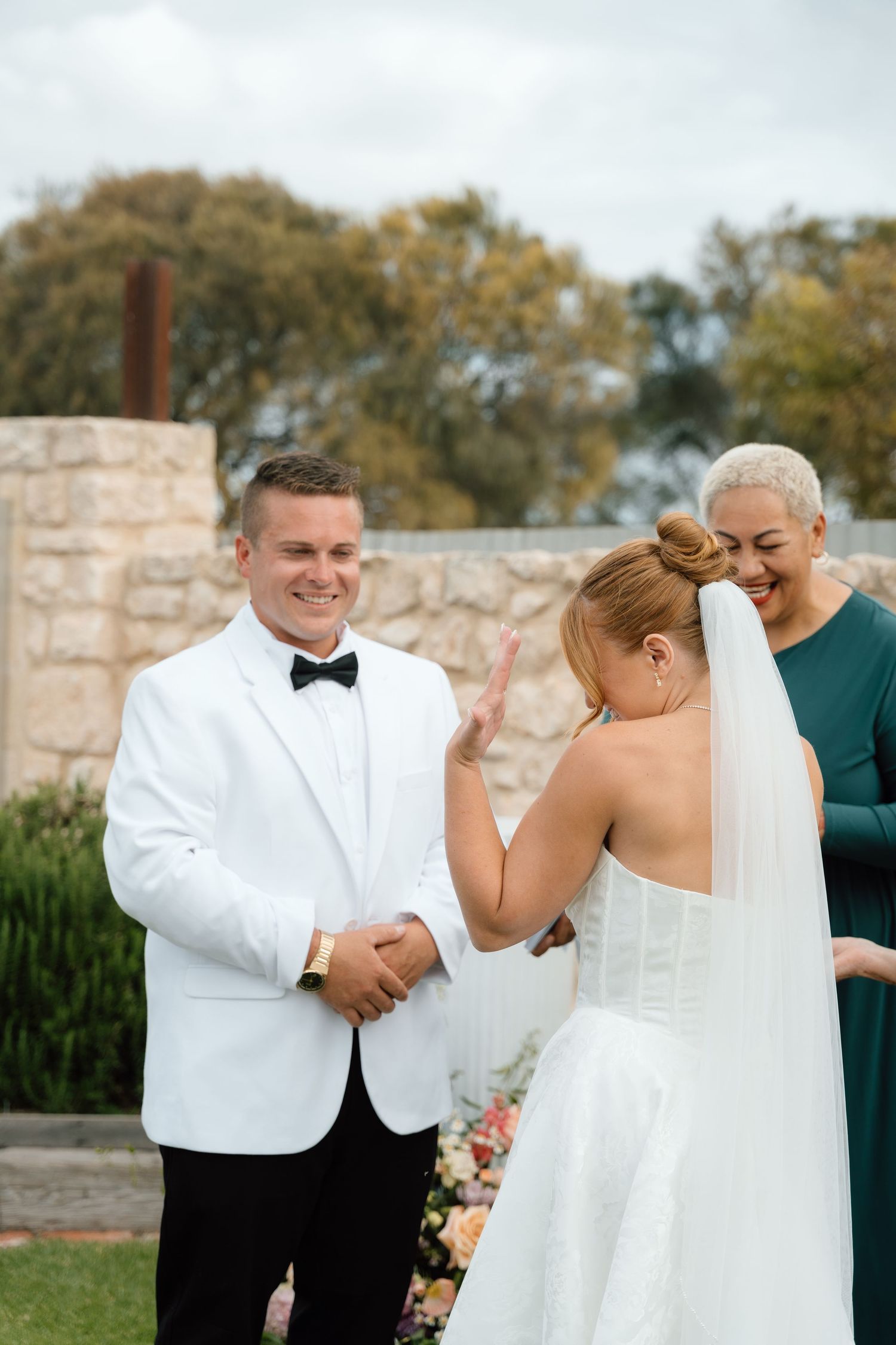 A couple shares a joyful moment during their wedding ceremony outdoors.