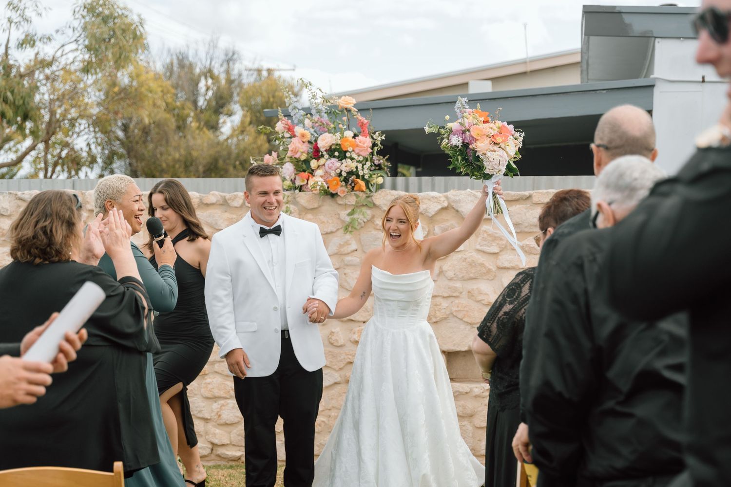 Wedding party celebrates with champagne toasts during outdoor reception at sunset.