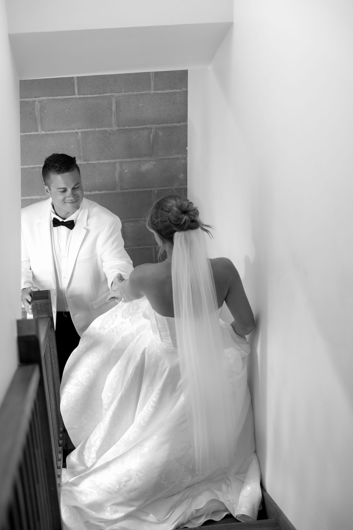 A couple in wedding attire photographed in a minimalist white hallway.