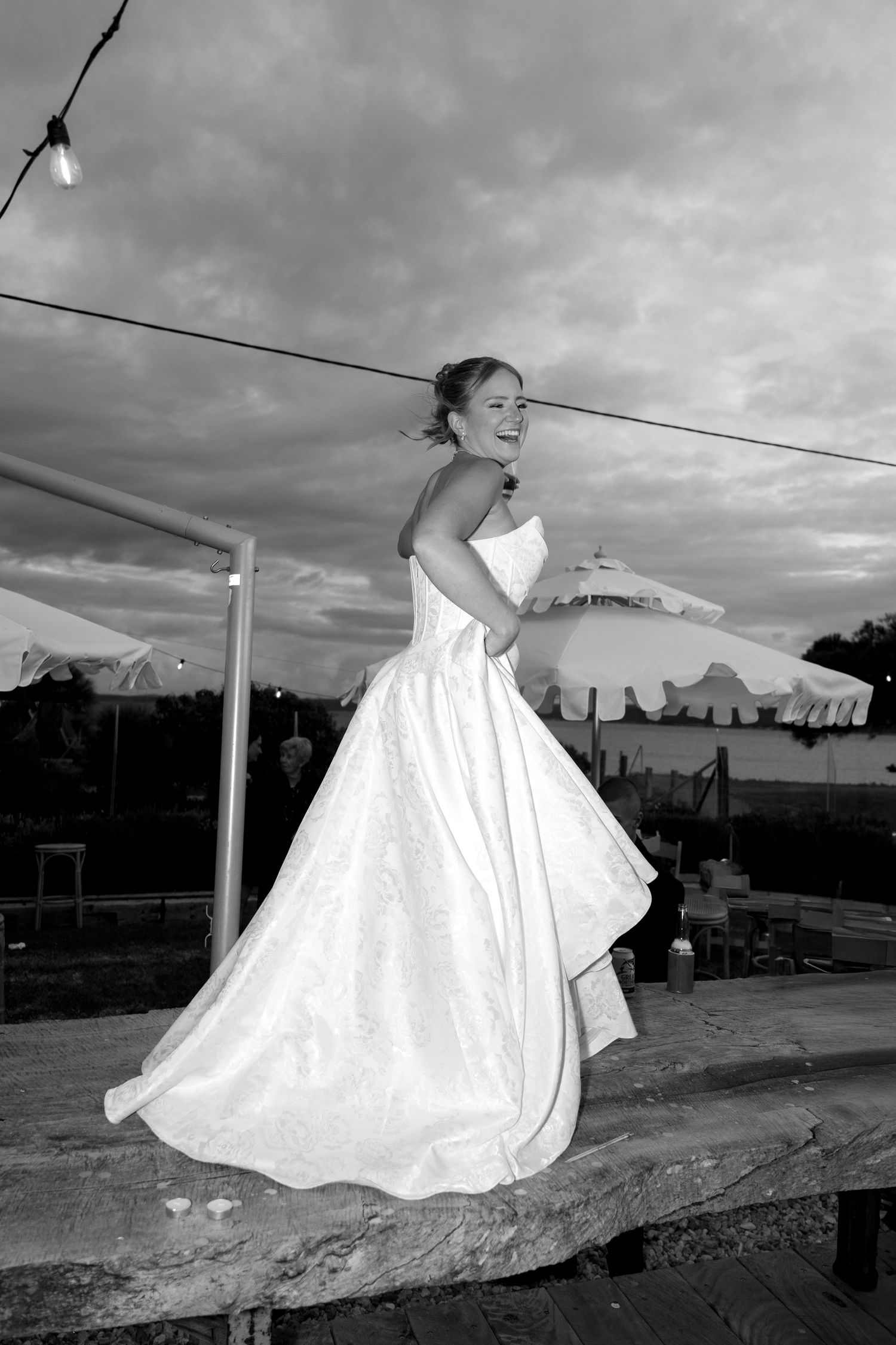 A black and white series showing the flowing movement of a wedding dress against a dramatic sky.
