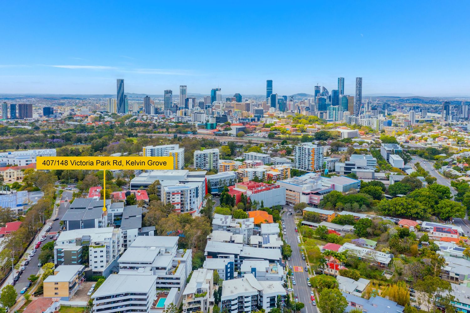 Bird's eye view of Victoria Park Rd Kelvin Grove showing surrounding suburbs and Brisbane city skyline.