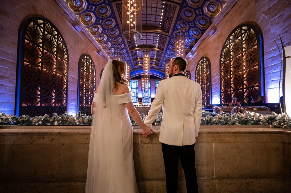 A couple shares a romantic moment in an ornately decorated venue with glowing arches and floral arrangements.