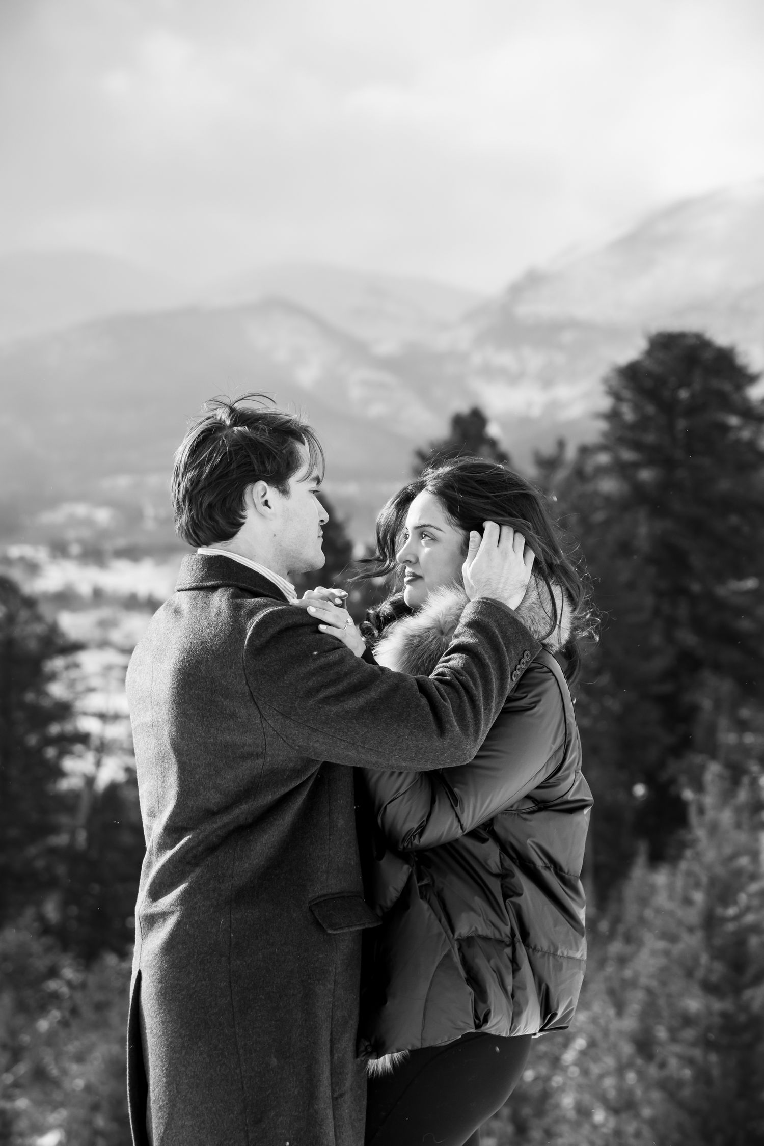 Romantic candid moment during winter engagement photos in Breckenridge Colorado with mountains in the background.