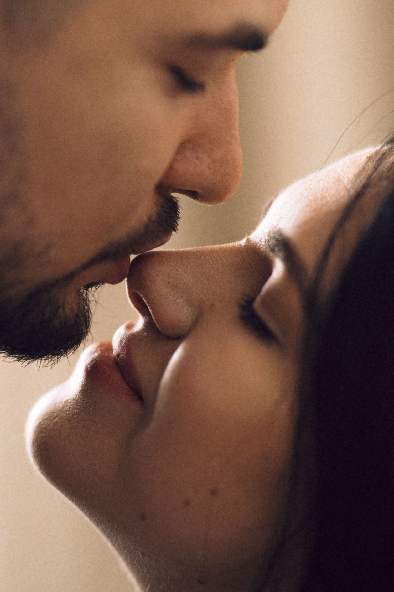 Romantic couple sharing an intimate kiss in warm lighting with soft focus.