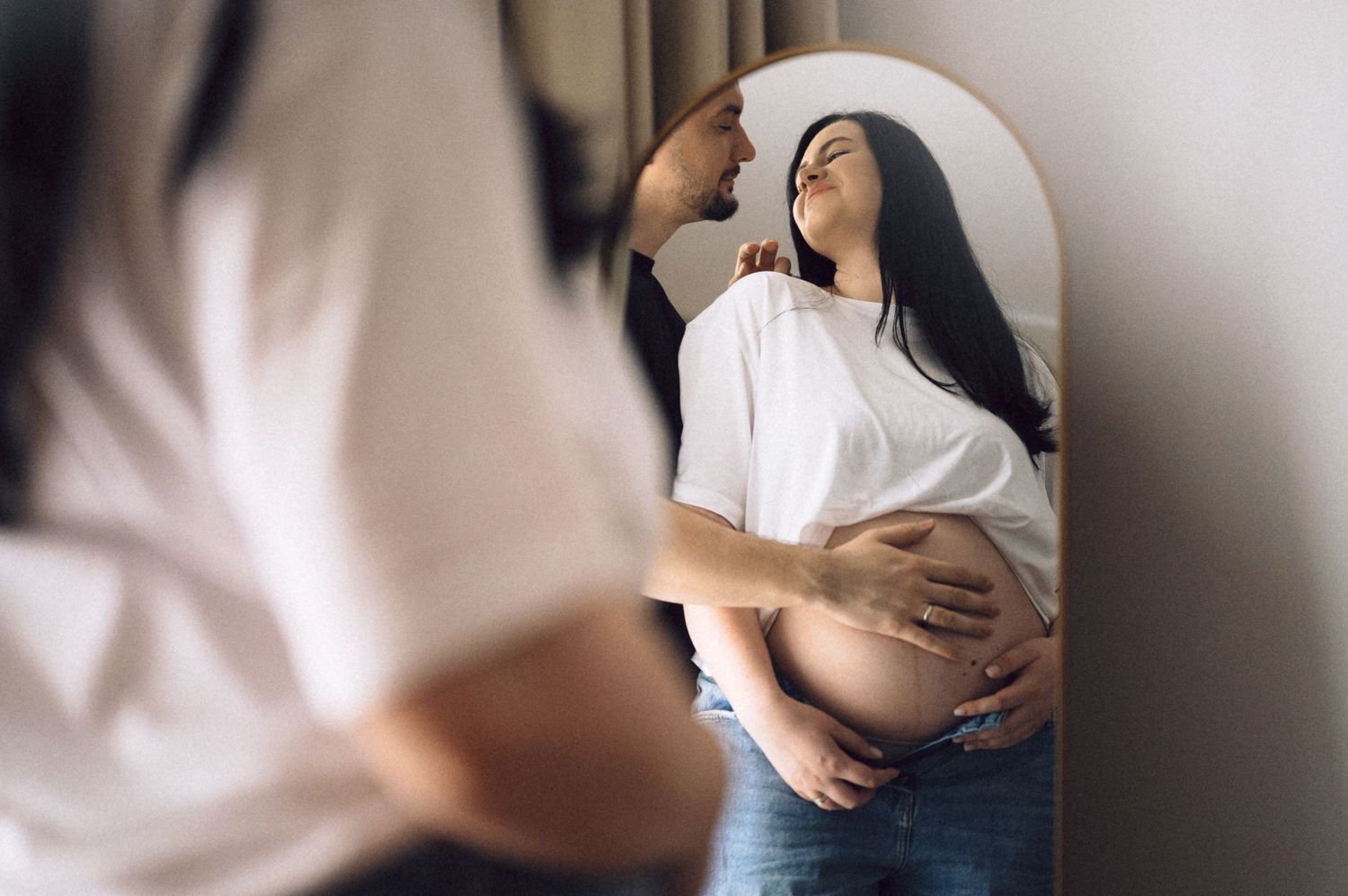 A person in white clothing lays back on a reflective surface with a soft dreamy mirror effect in the composition.
