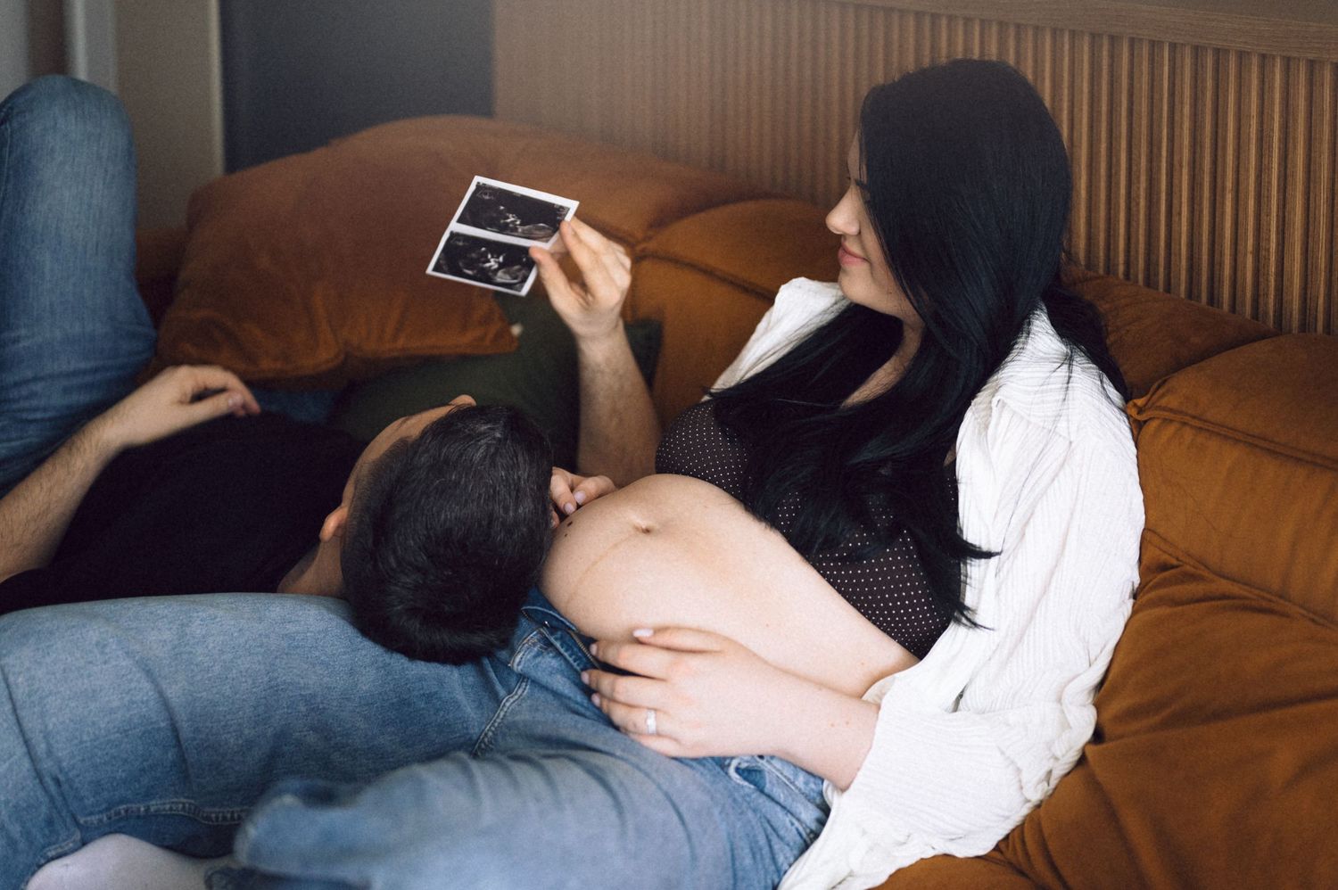 Someone lying on a couch or sofa while using a mobile device in a dimly lit room.