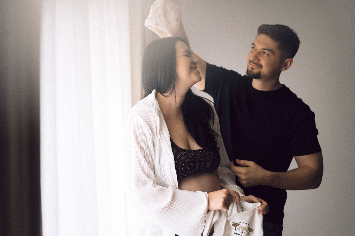 A couple in casual black and white outfits poses together in a series of romantic lifestyle photos against a neutral background.