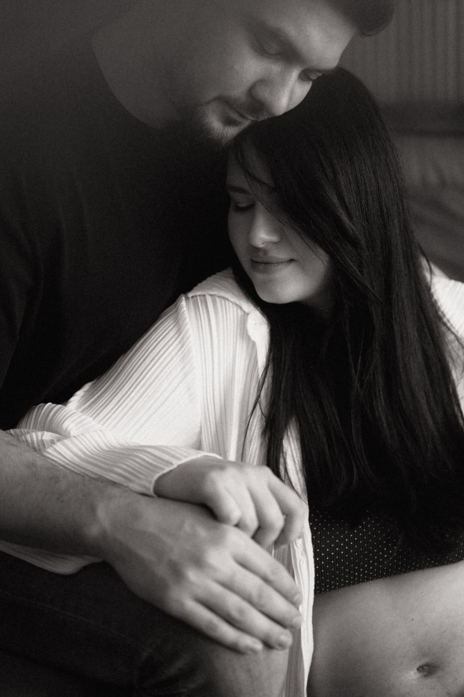 A series of black and white photographs showing hands gently embracing against a dark background.