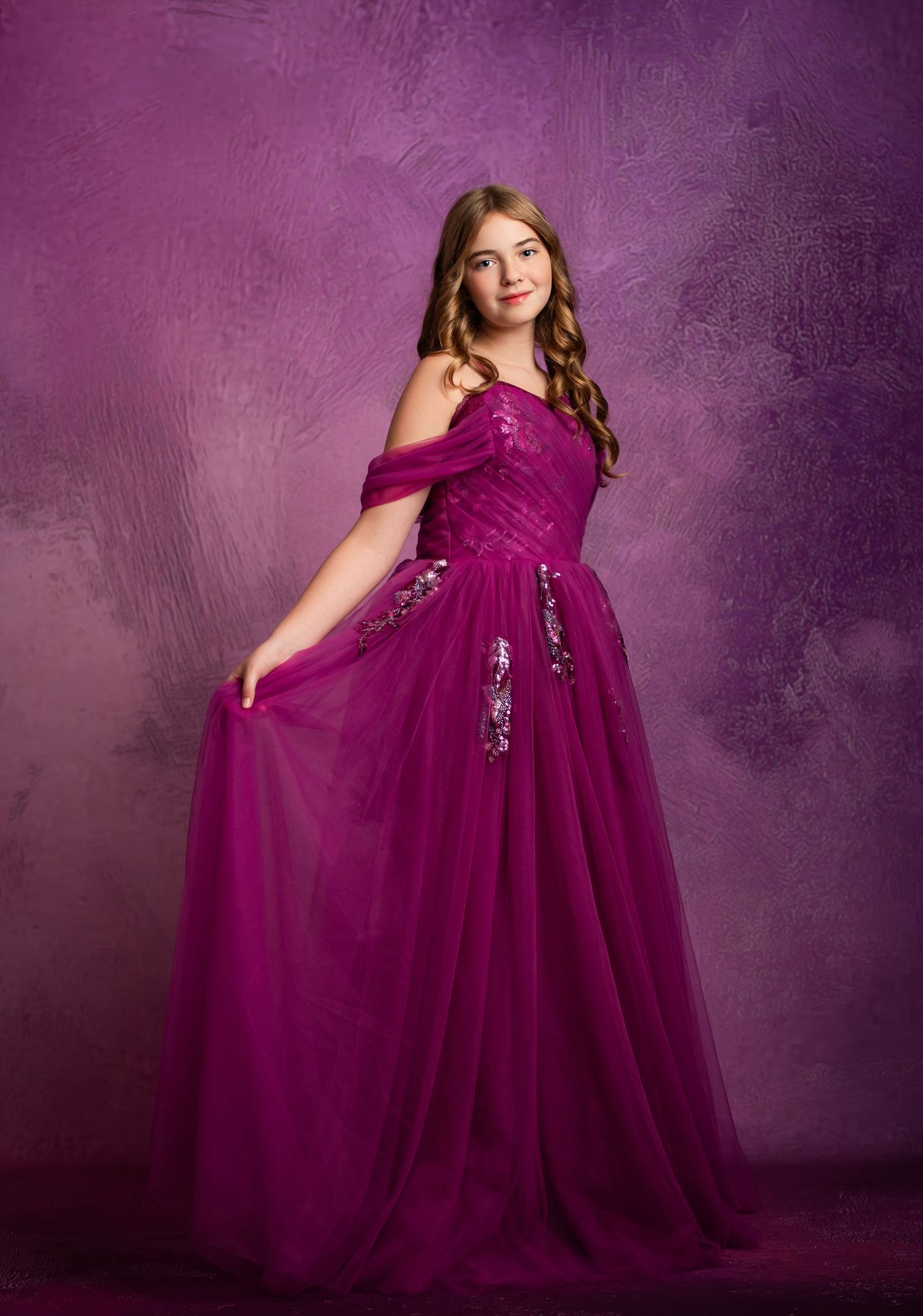 A vibrant red party dress captured against a deep red background in a studio setting.