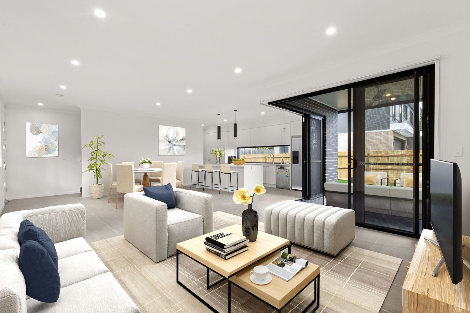 Contemporary open-plan living area with neutral tones, white sofas, and bifold doors opening to an outdoor space.