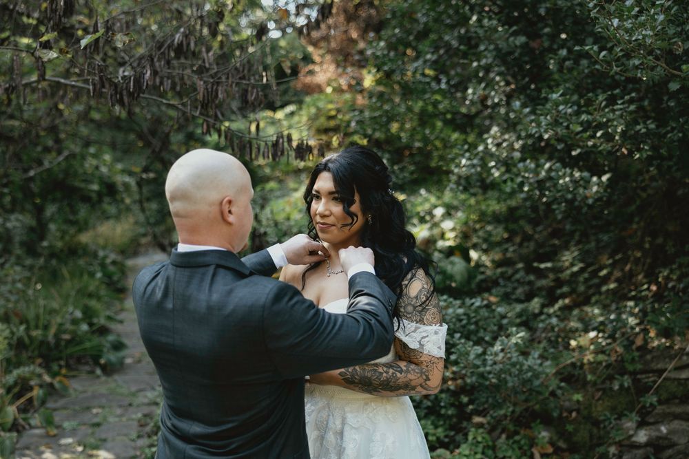 A couple shares an intimate moment together in a natural outdoor setting surrounded by lush greenery.