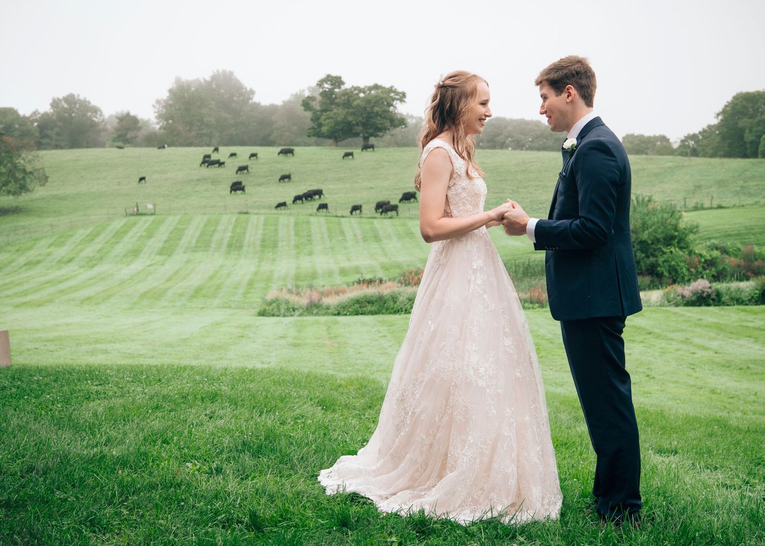 A couple shares a romantic moment in their wedding attire on a beautifully manicured green lawn.