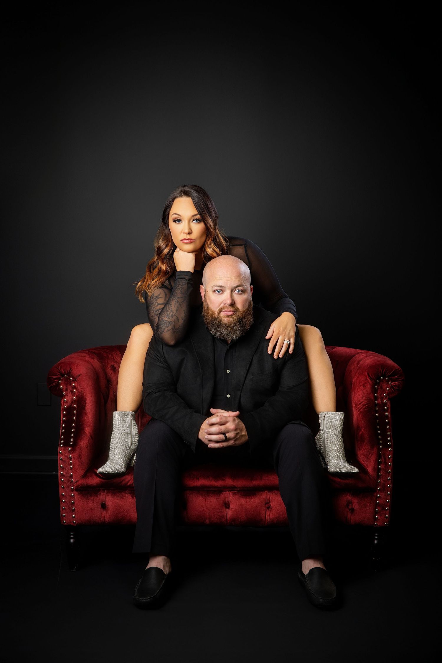 A dramatic photo series on a red velvet couch against black background showing playful poses between two people. Knoxville couple photograph