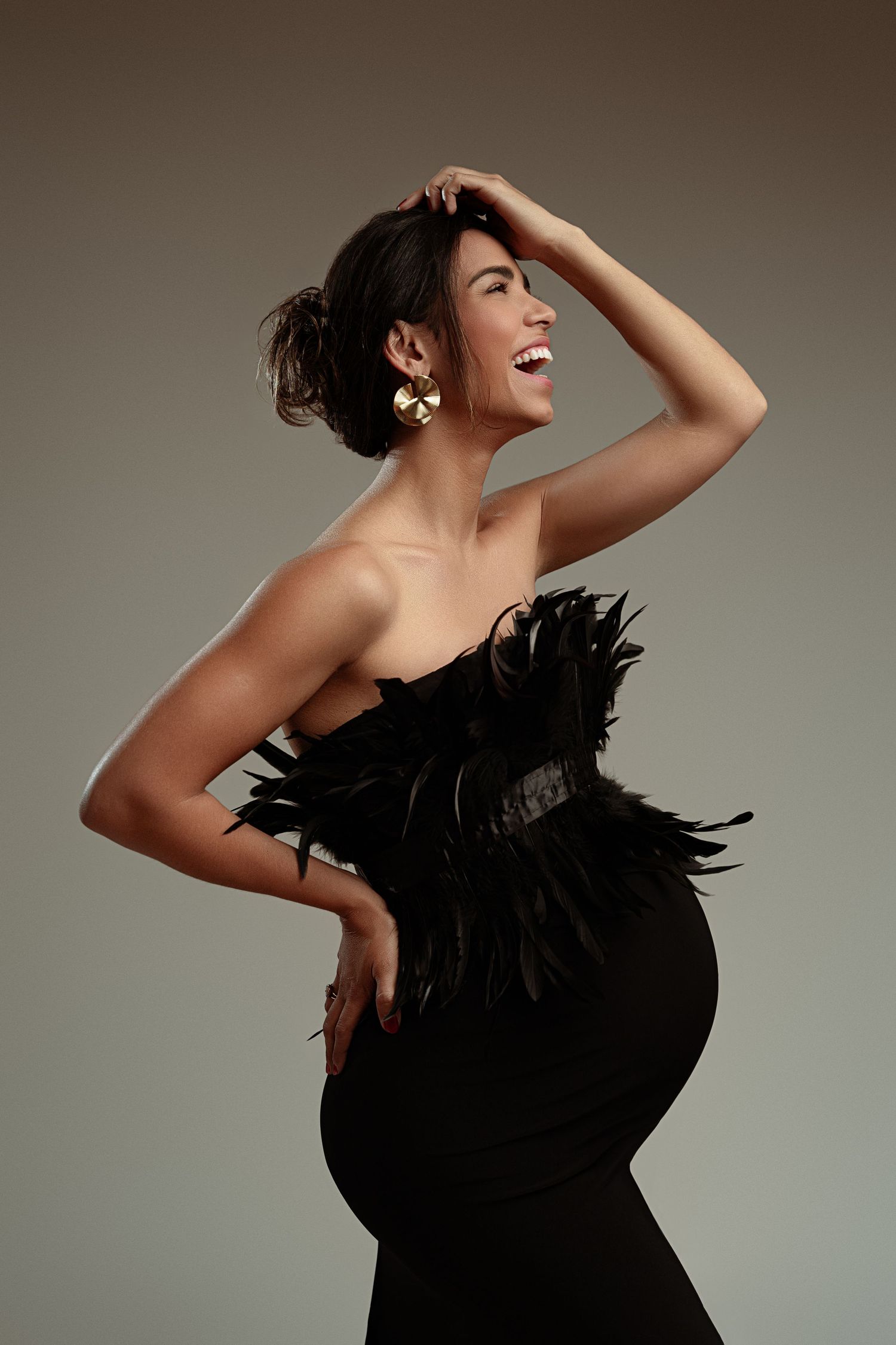 Joyful maternity portrait in black feathered dress with dramatic pose. maternity photographer Paloma Schell Houston TX