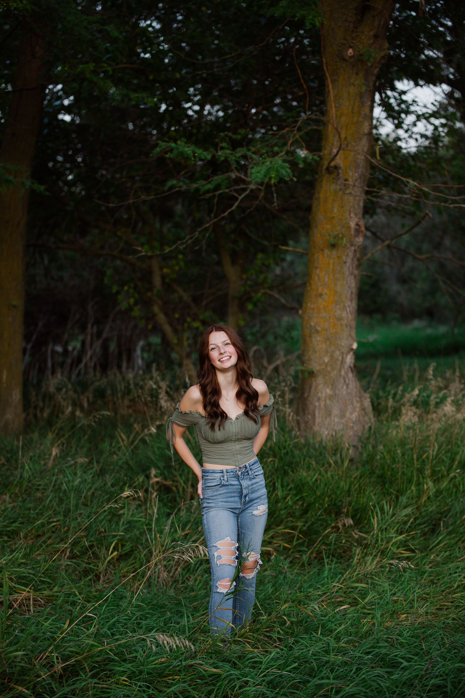 A woman in a denim dress poses in a vibrant wildflower meadow filled with yellow and red blooms on a sunny day.