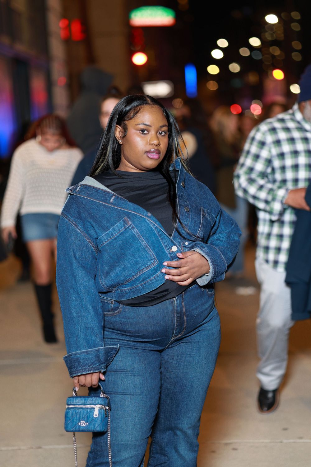 Person wearing denim outfit poses in various angles at night with blurred city lights in background.