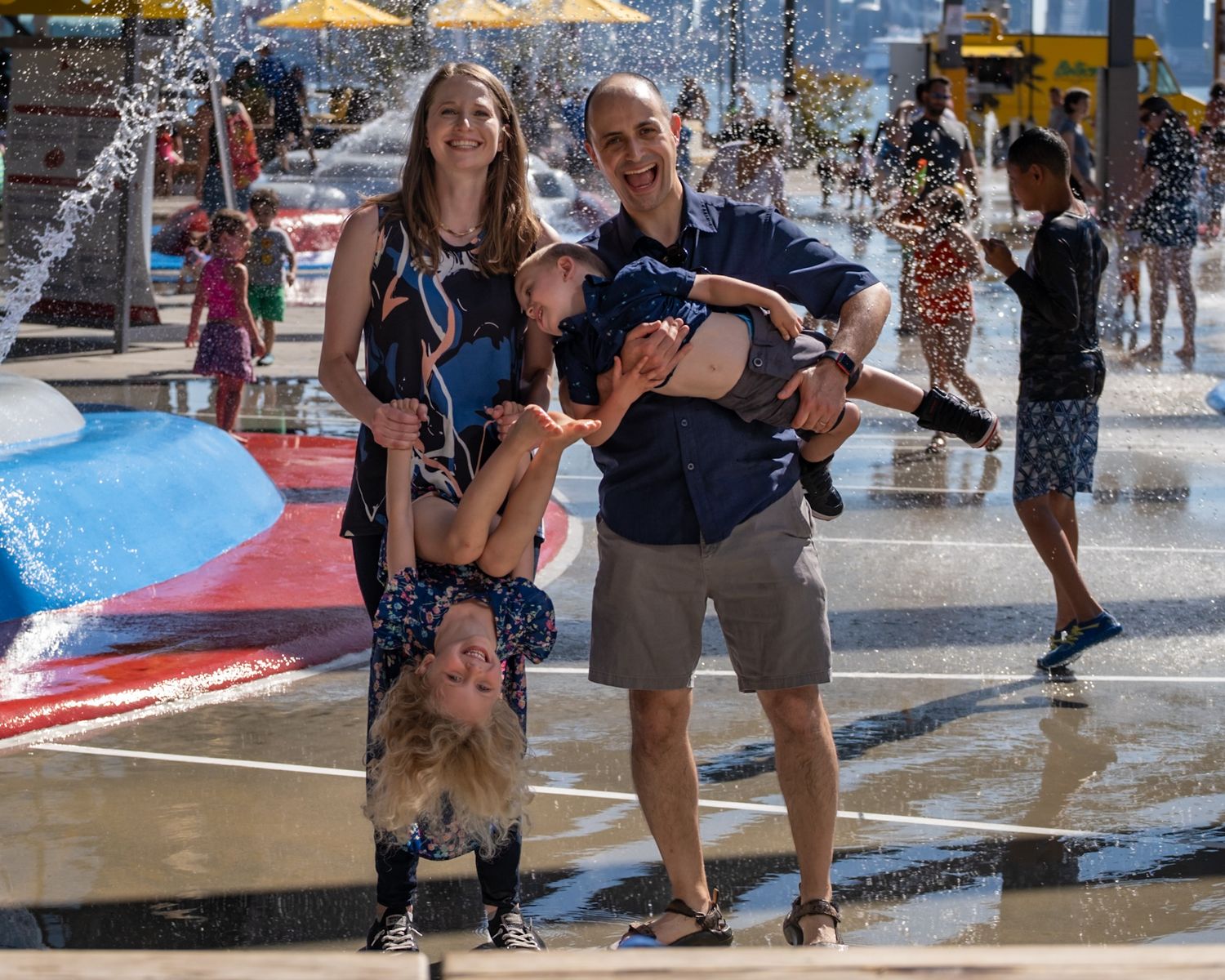 Family portrait session at The Shipyards, North Vancouver, dad holding child upside down laughing