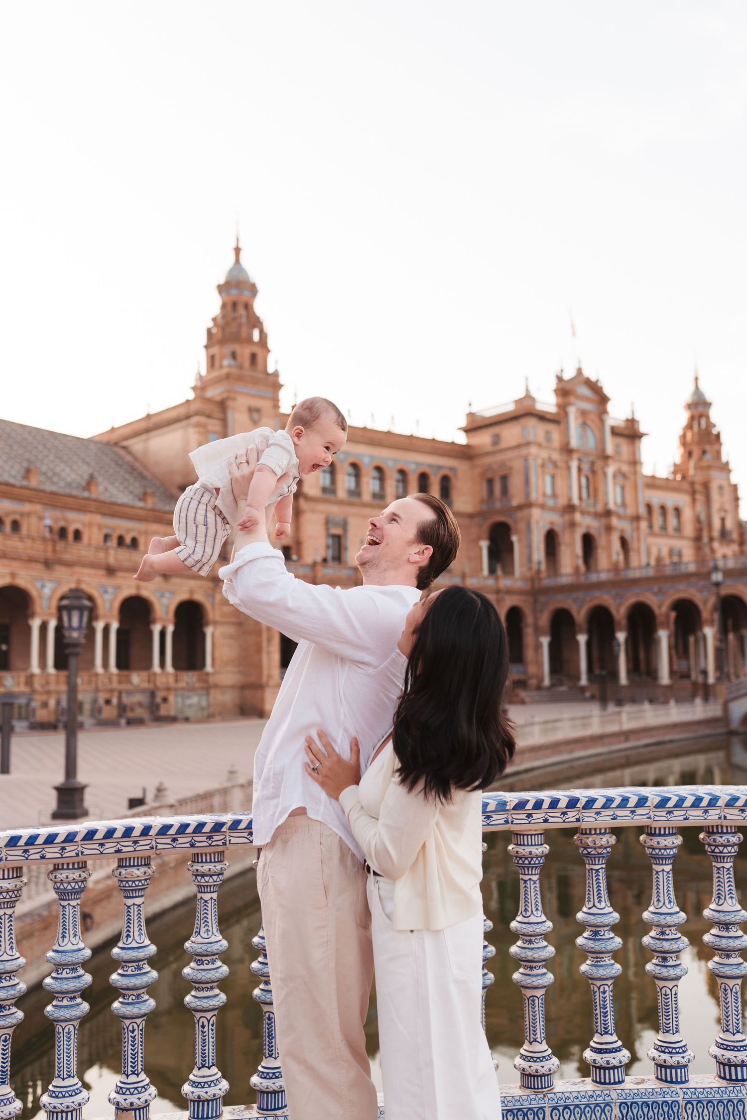 A family shares tender moments together in front of a beautiful Spanish-style church at sunset.