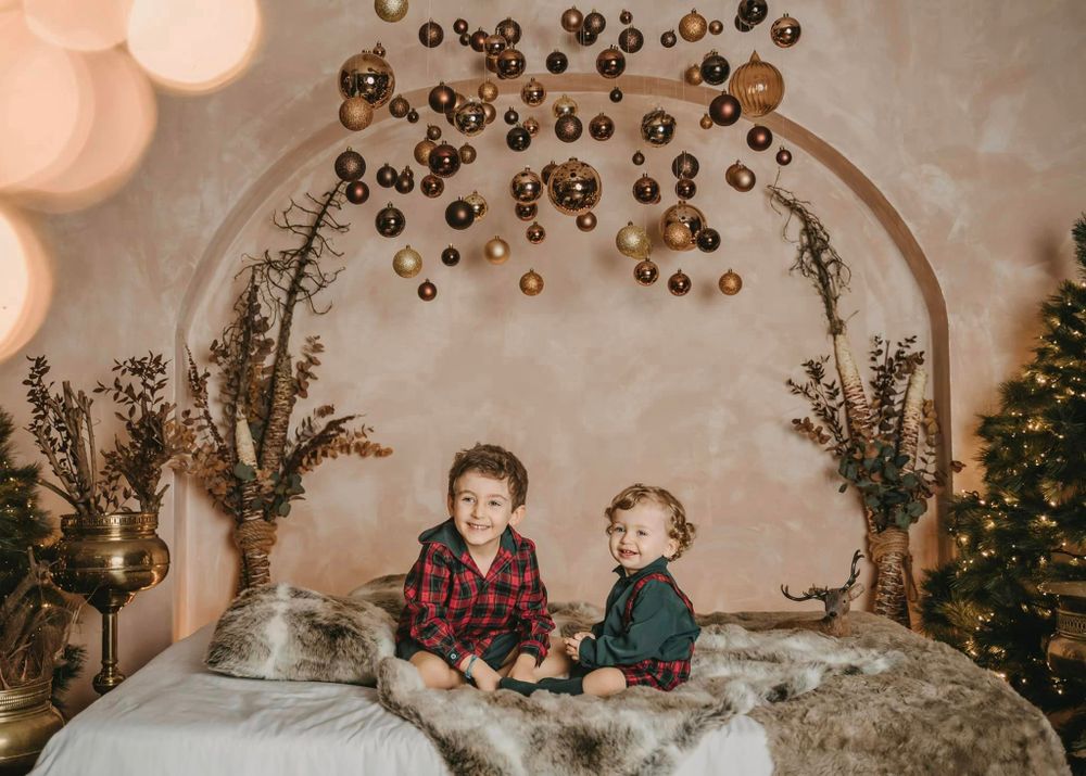 Holiday portrait with two children on bed under golden arch with Christmas decorations.