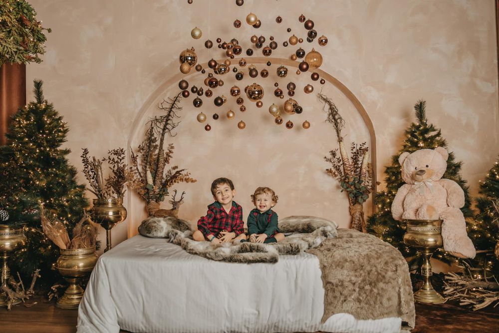 Children sitting on decorated bed with holiday arch and Christmas decor.