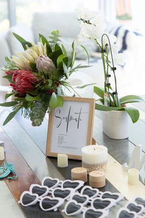 Wedding reception table decor with protea flower arrangement, seating chart and heart shaped decorations.