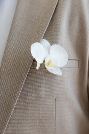 bride and groom wearing matching orchid ornaments
