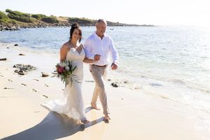 A couple walks together on a scenic beach during their portrait session