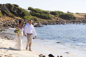 Newley weds walking along the beach after their wedding ceremony