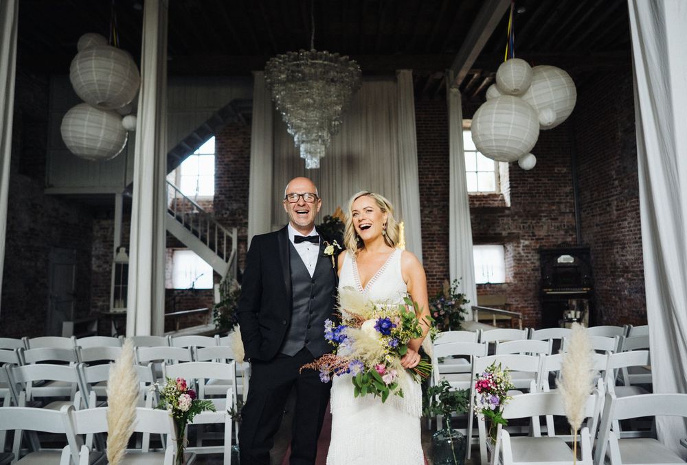 A couple celebrates their wedding day at a rustic venue decorated with white lanterns and exposed brick walls.
