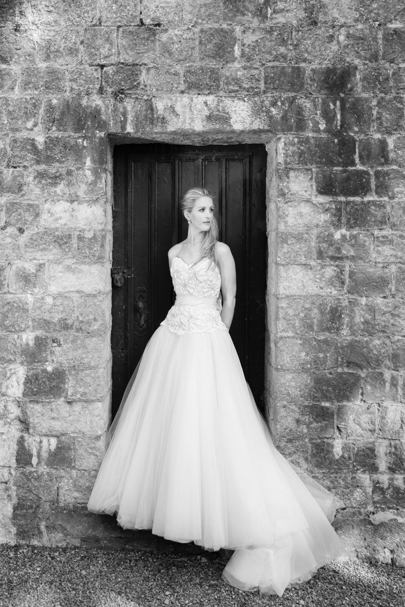 Bride leans on old boat house door