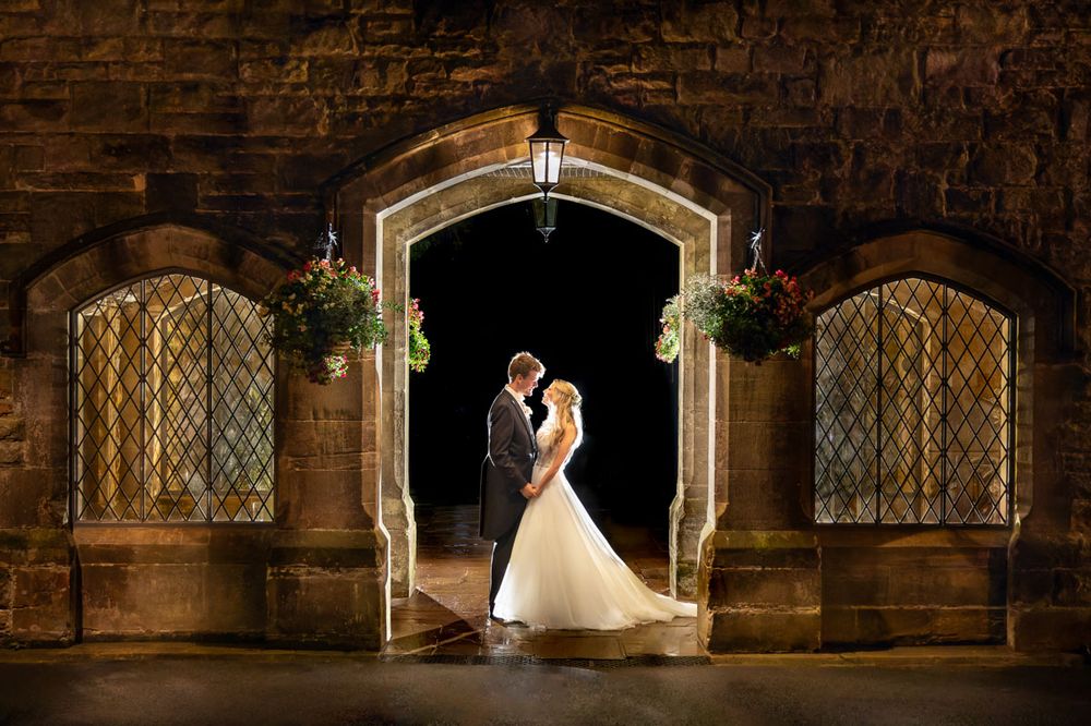 Striking night shot of bride and groom in medieval triple archway | Ashdown Park Hotel, East Sussex