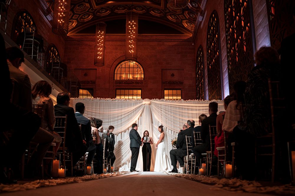 A silhouetted wedding ceremony in a dimly lit church with dramatic lighting and a white veil flowing in the air.