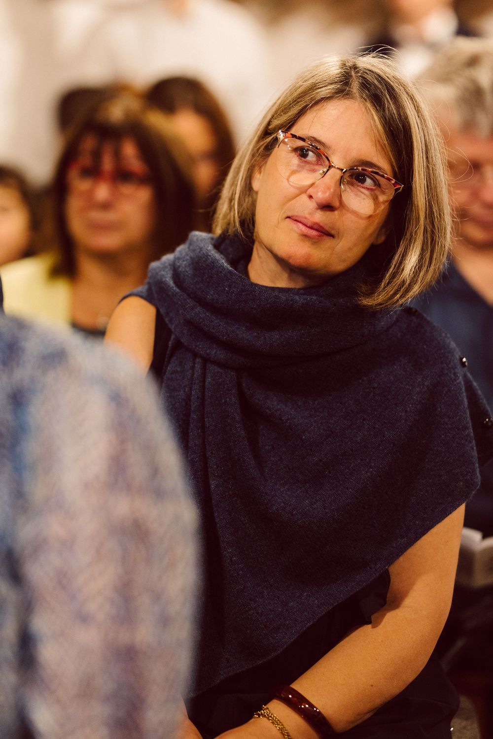 A sequence of photos showing a person in a navy cowl neck top and glasses turning their head from left to right.