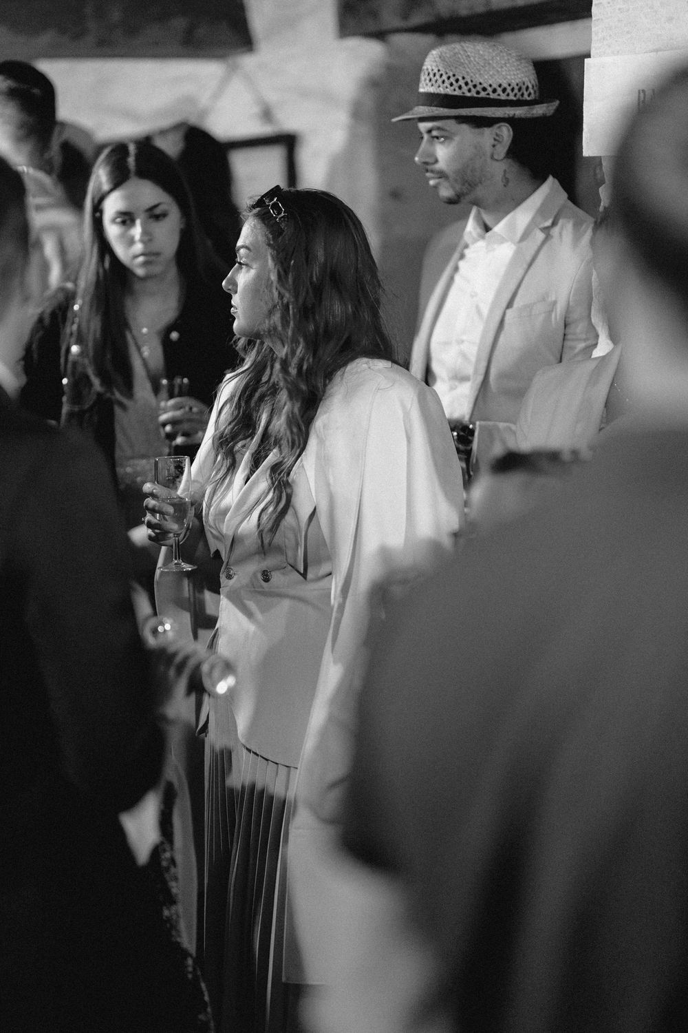Black and white photo of people in formal attire at an event, with blurred background and soft lighting.