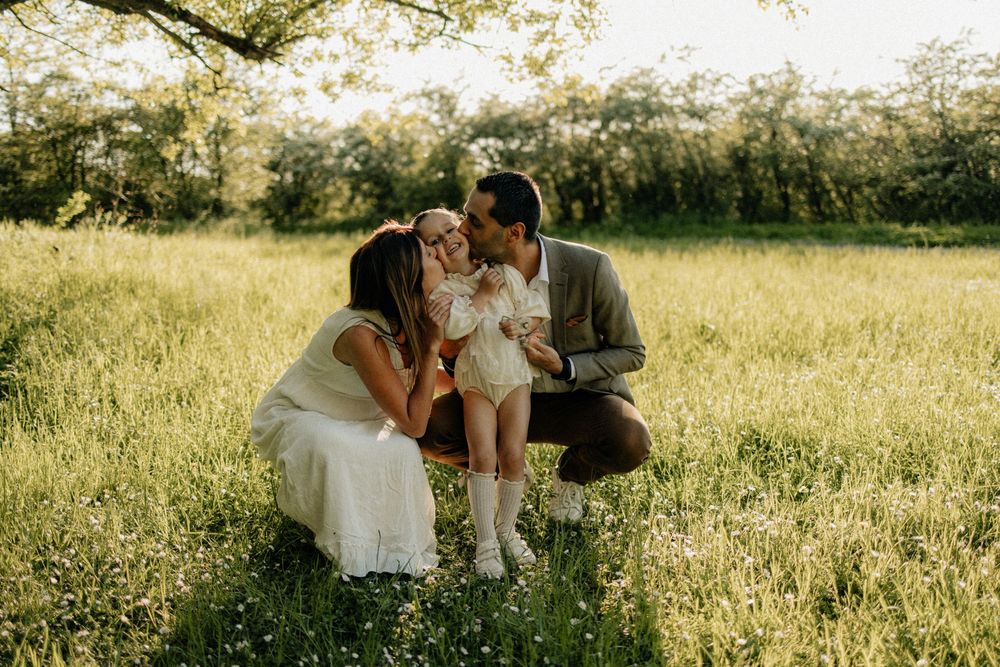 A couple shares an intimate moment while sitting in a golden sunlit meadow during a romantic outdoor photo session.