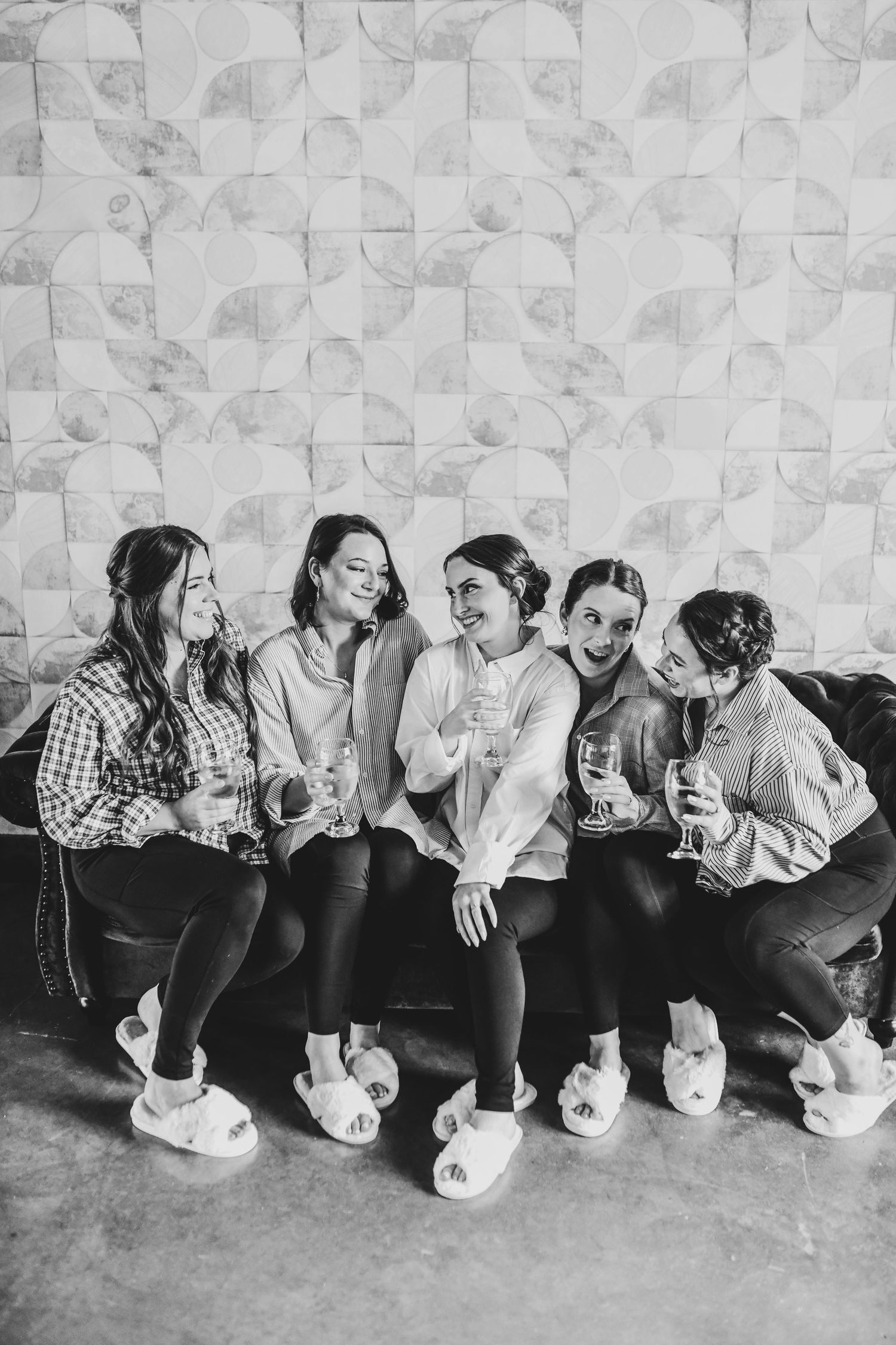 Bride laughing with her bridal party while raising champagne glasses during wedding morning preparations.