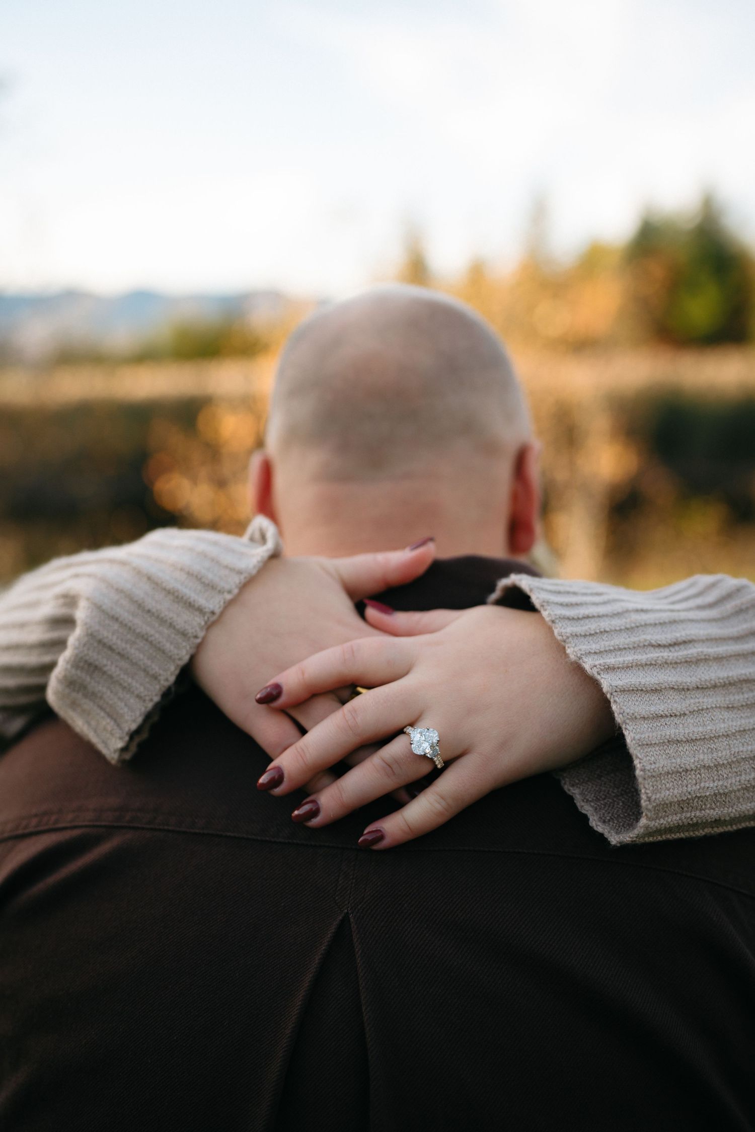 Close-up of hands showing engagement ring with a diamond sparkle in warm sunlight.