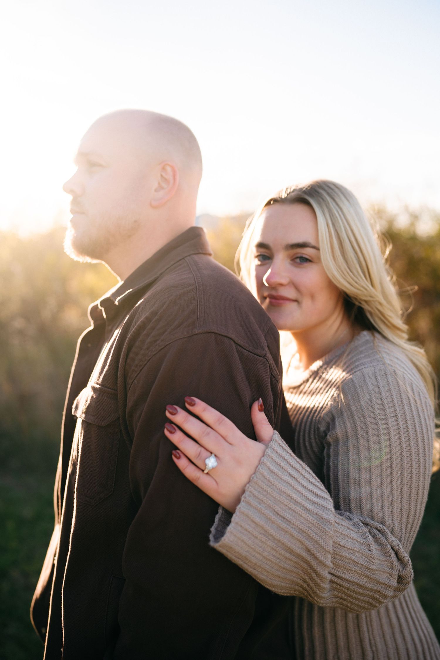 A couple shares an intimate moment during their engagement photoshoot with golden sunlight behind them.