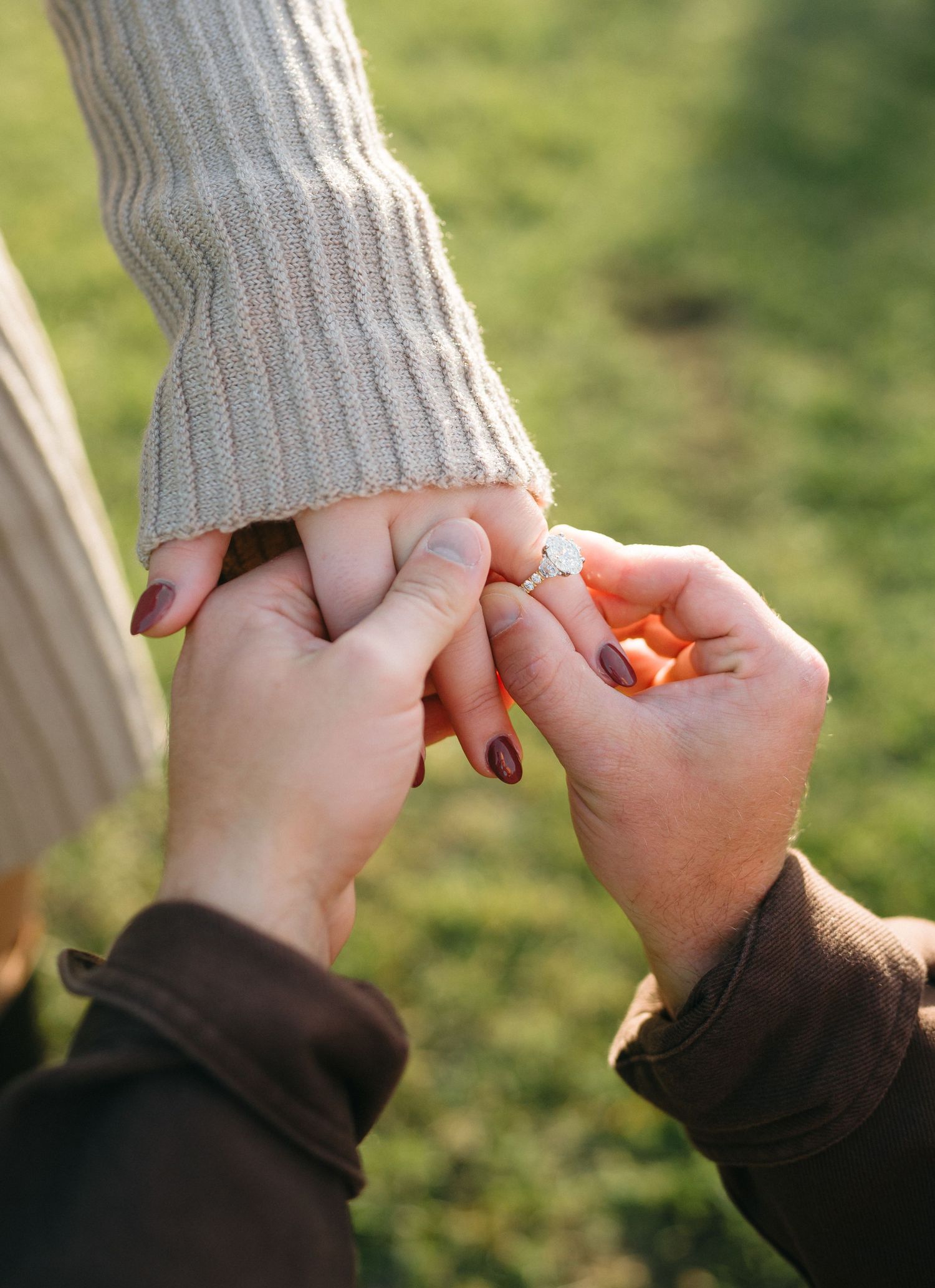 Close-up sequence showing hands revealing an engagement ring against a sweater background.