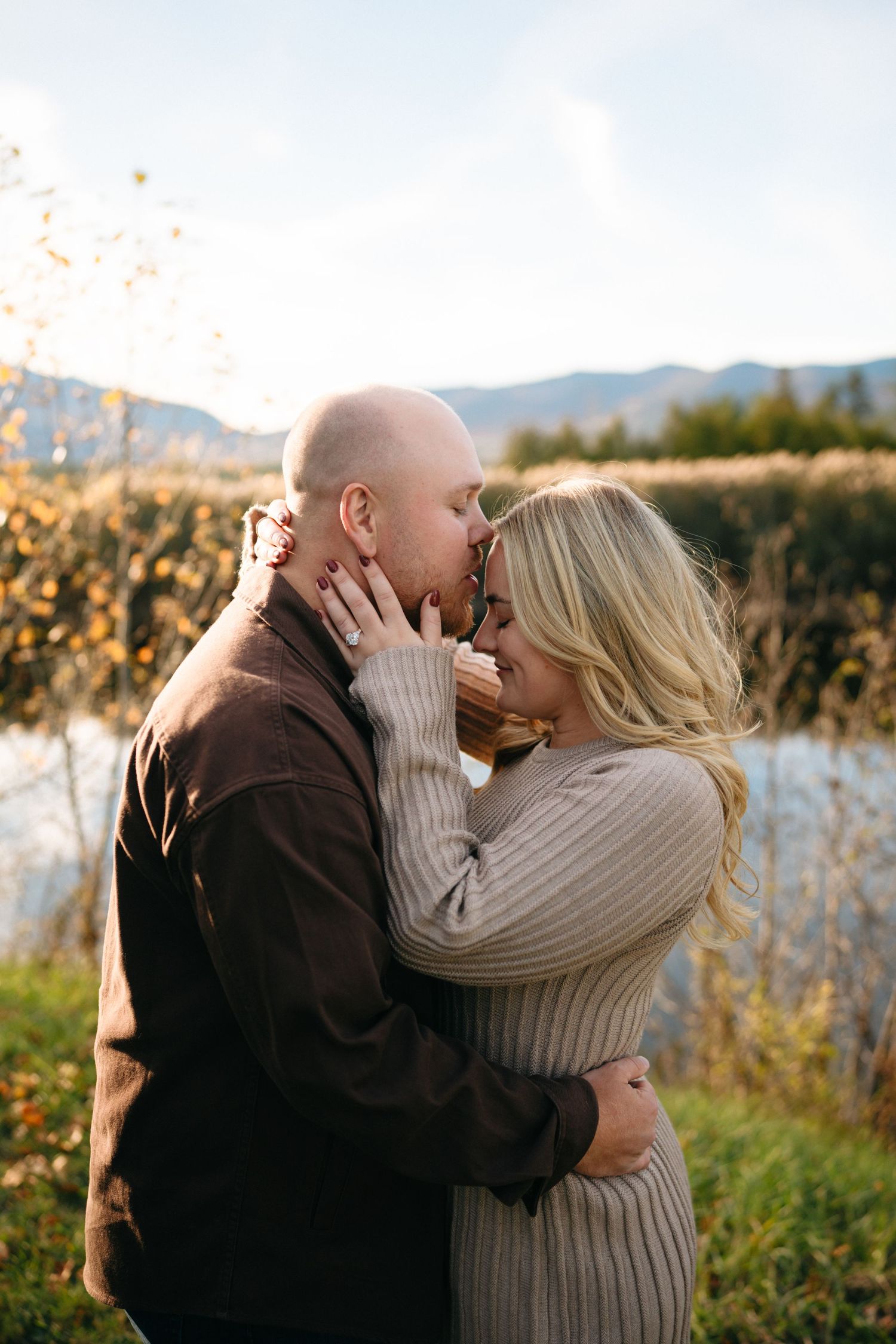 A romantic couple shares intimate kisses in a series of outdoor photos with mountains and autumn foliage in the background.