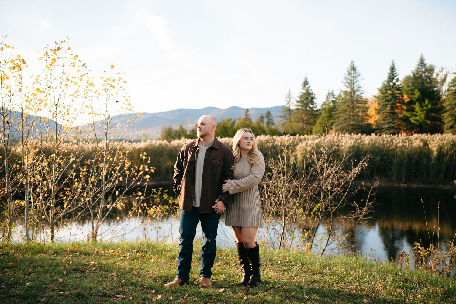 Scenic lakeside engagement photos with mountains and autumn foliage creating a romantic backdrop.