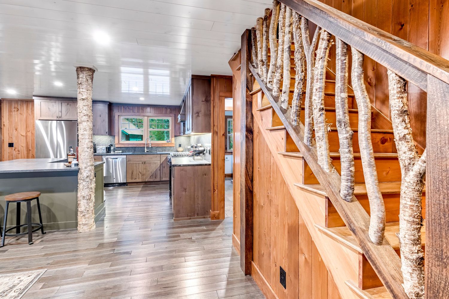 Open concept living space with unique birch tree staircase railing and hardwood floors.
