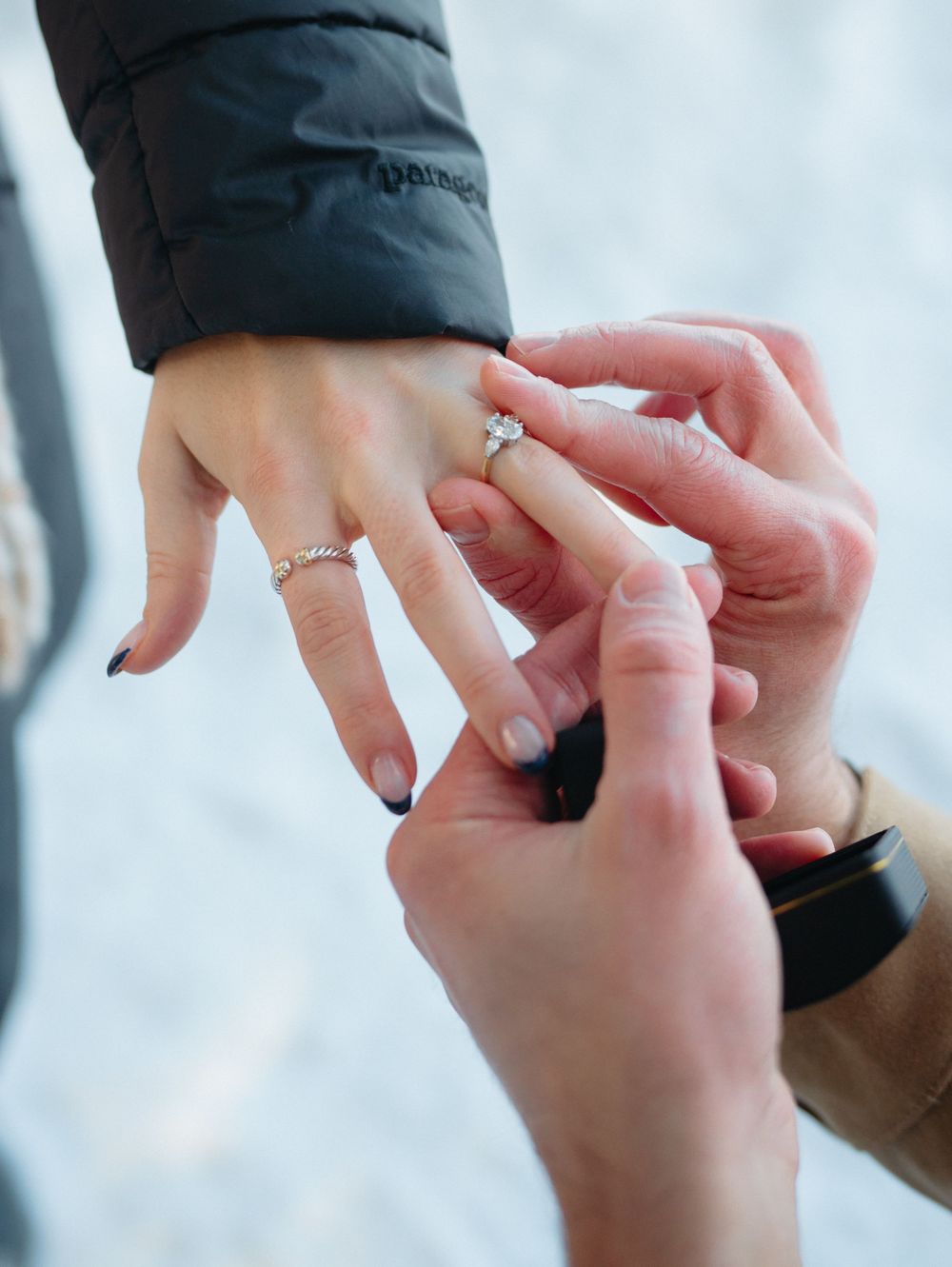 Close-up of hands placing an engagement ring during a romantic proposal moment.
