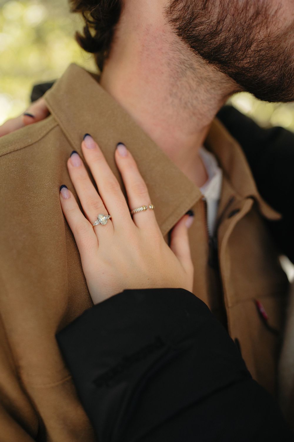 A close-up series showing a hand wearing a black sleeve and engagement ring against a brown coat background.