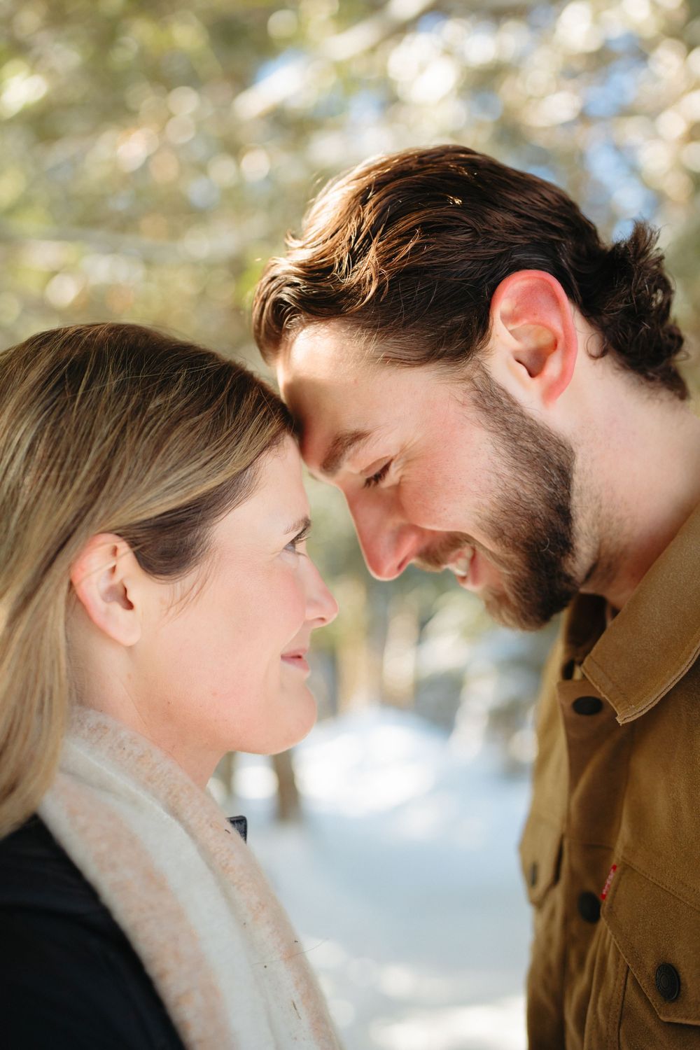 A romantic winter engagement photo series showing a couple in close intimate poses against a snowy outdoor backdrop.