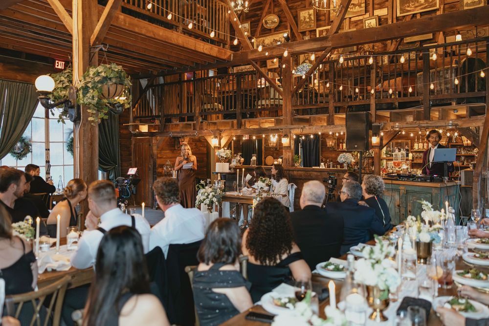 Rustic barn wedding reception venue with wooden beams and elegant chandeliers creating a warm, romantic atmosphere.