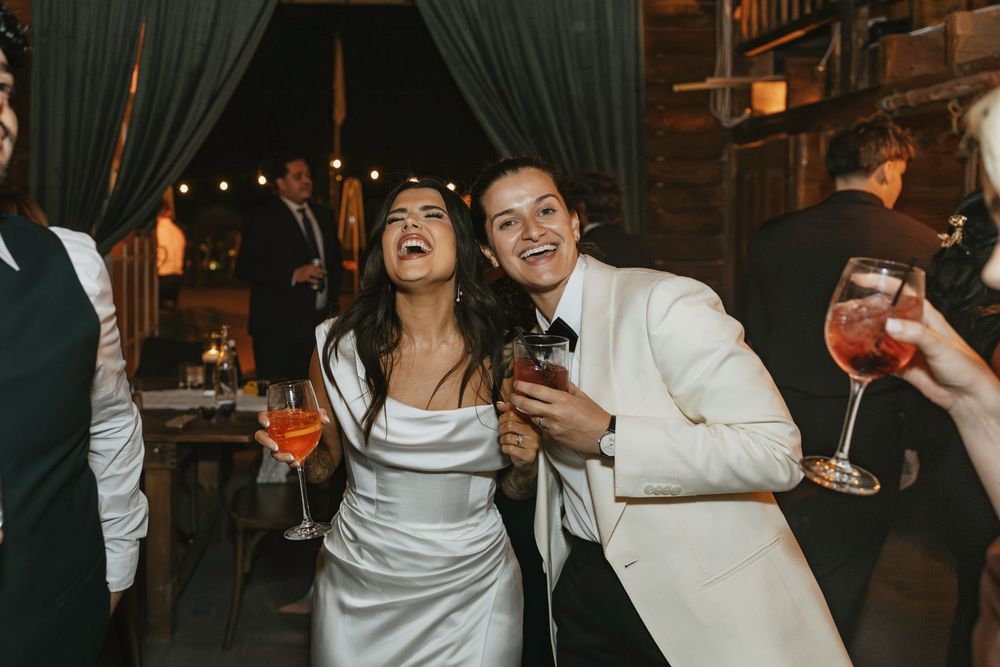 Wedding couple shares joyful moment with drinks at rustic barn reception.